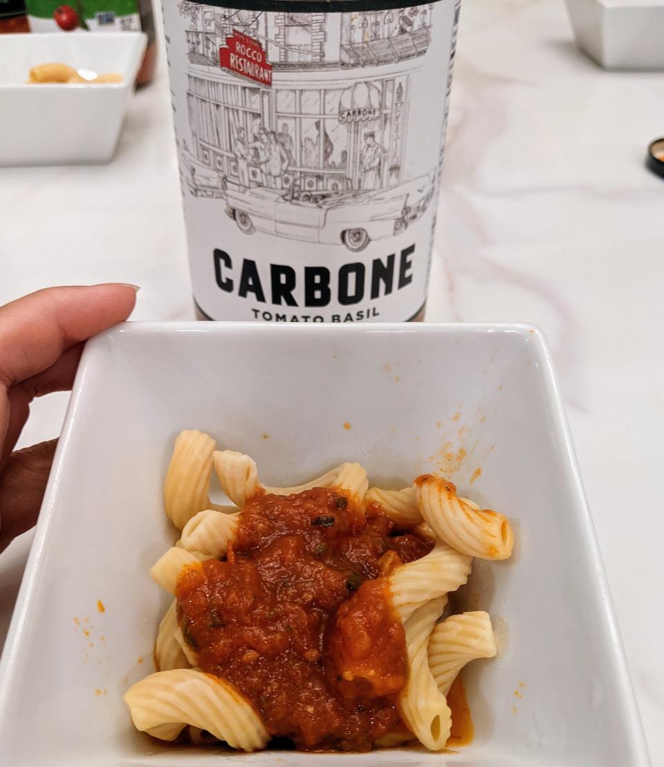 Jar of carbone red sauce behind a small white bowl of pasta