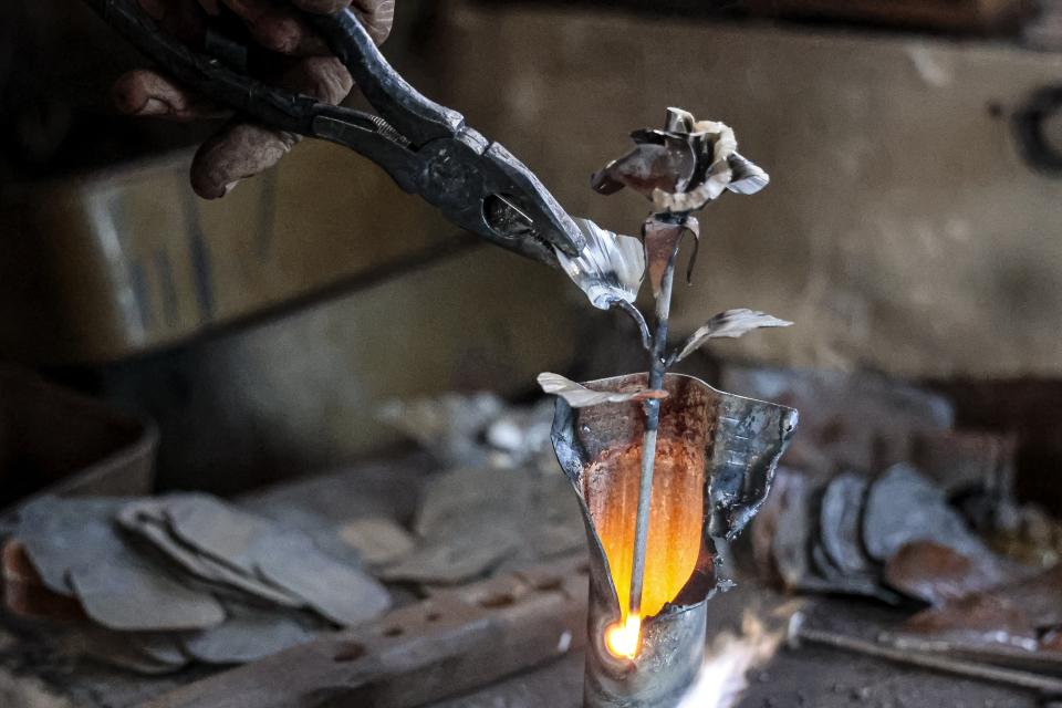 Viktor Mikhalev works in a workshop in his house in Donetsk, Russian-controlled Donetsk region, eastern Ukraine, Saturday, March 4, 2023. Mikhalev is transforming weapons and ammunition into flowers of war. Mikhalev, trained as a welder, lives and works in a house whose fence and door are decorated with forged flowers and grapes. (AP Photo/Alexei Alexandrov)