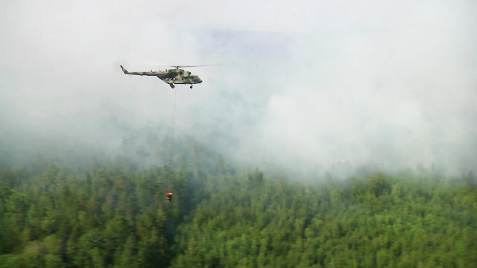 A still image, taken from a video footage shows a helicopter dropping water over a burning forest in Krasnoyarsk region, Russia August 4, 2019. Video footage taken August 4, 2019. REUTERS via Reuters TV