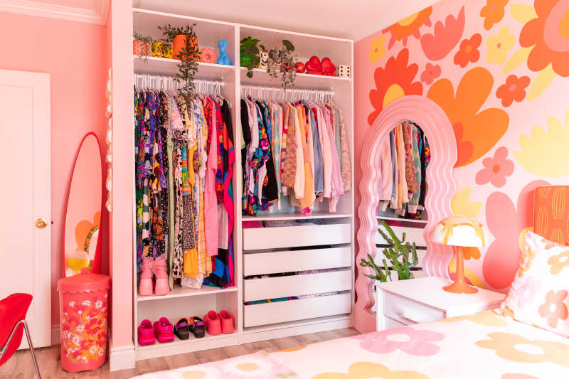 Colorful clothing organized in closet of pink and orange bedroom.
