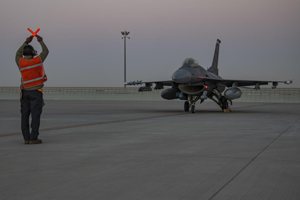 In this handout photo from the U.S. Air Force, an airman guides an F-16 Fighting Falcon during training at Al-Udeid Air Base, Qatar, Jan. 24, 2022. As over a million World Cup fans fill stadiums with cheers and carry heady optimism through the streets of Doha, some 8,000 American troops are running air wars in Afghanistan, Iraq, Syria and other hotspots in the Middle East mere miles away. (U.S. Air Force/Capt. Mahalia Frost, via AP)