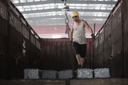 A worker helps load steel bars onto a truck at warehouse of the Baifeng Iron and Steel Corporation in Tangshan in China's Hebei Province August 3, 2015. REUTERS/Damir Sagolj