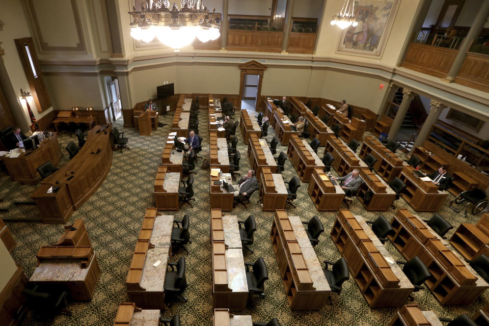 FILE - In this May 15, 2020 file photo few legislators sit in a nearly empty House chamber during a special legislative session inside the state Capitol in downtown Cheyenne, Wyo., during the coronavirus pandemic. Wyoming lawmakers have again decided not to adopt a hate crimes law in the state where gay college student Matthew Shepard was killed more than 20 years ago. Wyoming is one of just three states that haven't enacted hate crimes legislation since Shepard was beaten and left for dead in Laramie in 1998. (Michael Cummo/The Wyoming Tribune Eagle via AP, File)