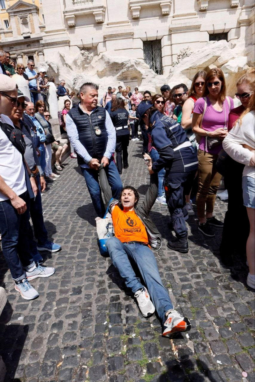 A detained climate activist is dragged away by police during a demonstration at Trevi Fountain against fossil fuels, in Rome, Italy May 21, 2023 in this image obtained from social media. Alessandro Penso/MAPS  / Credit: ALESSANDRO PENSO/MAPS