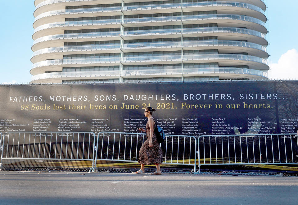 A person walks by a screen featuring the names of the victims of the Champlain Towers South condo collapse (Joe Raedle / Getty Images)