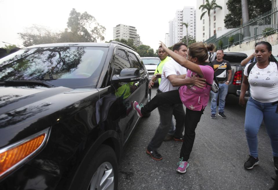 Una simpatizante del presidente venezolano Nicolás Maduro patea un auto que forma parte de la caravana que transporta al autoproclamado presidente interino de Venezuela, Juan Guaidó, durante su llegada a un mitin en Caracas el viernes 29 de marzo de 2019. (AP Foto/Boris Vergara)