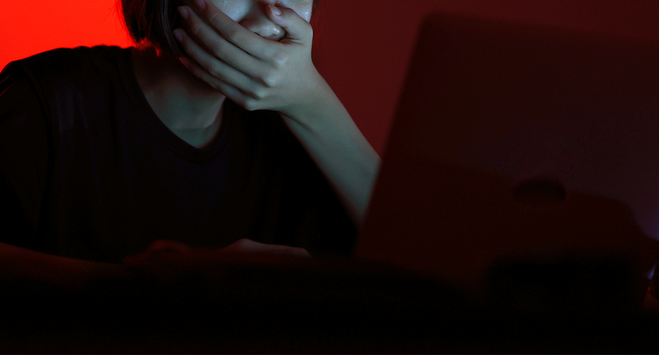 A distressed child is seen behind a laptop. 