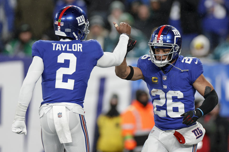 New York Giants running back Saquon Barkley (26) celebrates with quarterback Tyrod Taylor (2) after scoring a touchdown against the Philadelphia Eagles during the second quarter of an NFL football game, Sunday, Jan. 7, 2024, in East Rutherford, N.J. (AP Photo/Adam Hunger)