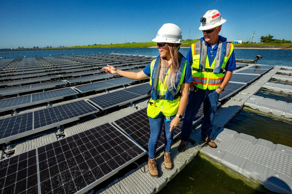 Duke Energy project manager Shayna White and environmental specialist Tommy O'Neal walk on floating solar panels covering two acres of a 1,200-acre cooling pond at the Hines Energy Complex in Bartow. The floating array is expected to be complete in five or six months.