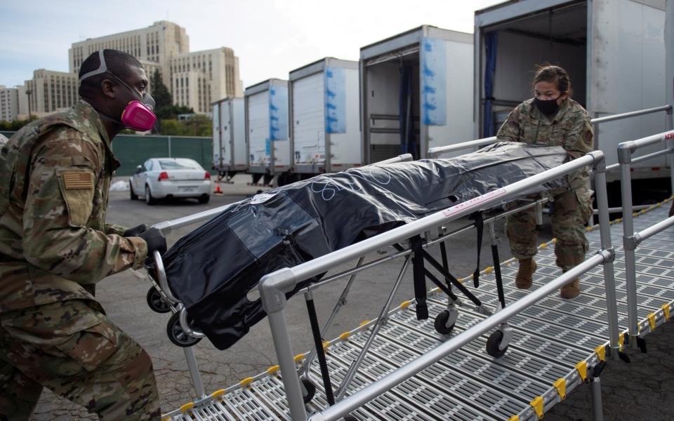 California National Guard personnel wheel a deceased person lying on a gurney to a secondary temporary refrigerated storage facility - REUTERS