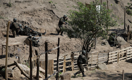 Brazilian Army soldiers take cover during a shootout with drug gangs during an operation in Alemao slums complex in Rio de Janeiro, Brazil August 20, 2018. REUTERS/Ricardo Moraes