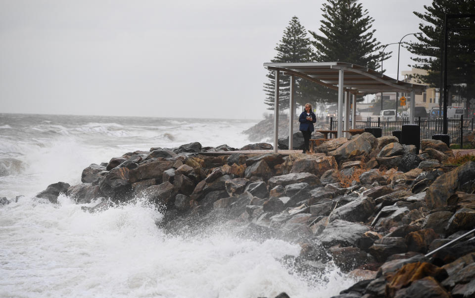 A woman takes a photo of the high tide and a storm surge at Brighton Beach, Adelaide as a storm front starts to hit the coast line in 2018. South Australia is set for two cold fronts this week.