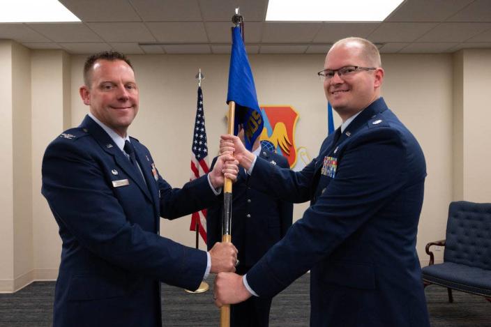 From left, U.S. Air Force Lt. Col. Justin Wolthuizen, 375th Medical Support Squadron incoming commander, accepts guidon from Col. Richard Woodruff, 375th Medical Group commander, during a change of command ceremony at the Deltgen Auditorium on Scott Air Force Base. The 375th MDSS supports healthcare delivery by managing a group budget and manpower programs for more than 700 staff members.