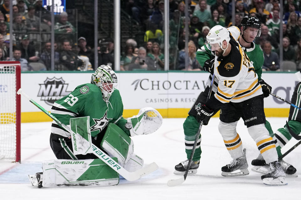 Dallas Stars goaltender Jake Oettinger (29) prepares to block a shot under pressure from Boston Bruins left wing Nick Foligno (17) in the second period of an NHL hockey game, Tuesday, Feb. 14, 2023, in Dallas. The Stars Esa Lindell, right rear, helps defend on the play. (AP Photo/Tony Gutierrez)