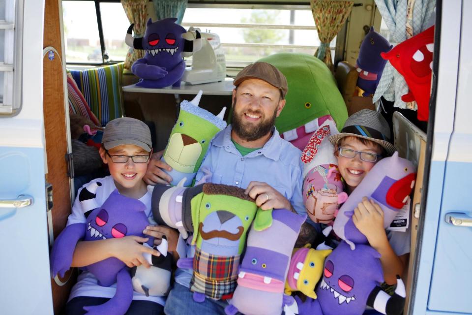 This photo taken on May 23, 2013 shows Ray Tollison, center, with his twin sons, Ben, left, and Sam posing with monster dolls in their van at their home in Fort Collins, Colo. The Tollisons launched Monster to Love, a company that makes plush monster toys. (AP Photo/Ed Andrieski)