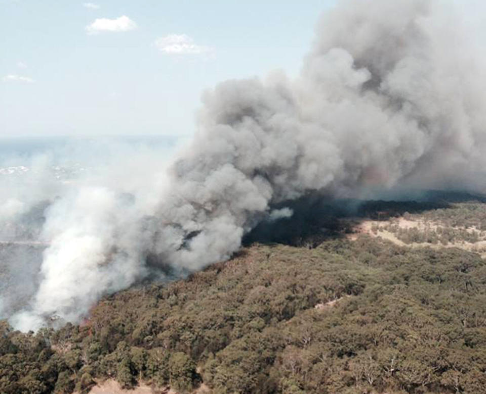 In this photo provided by the New South Wales Rural Fire Service, smoke rises from a wildfire near Lake Macquarie, New South Wales, Australia, Wednesday, Oct. 23, 2013. Winds that were fanning wildfires and showering embers on threatened communities eased late Wednesday, after scores of Australians evacuated their homes in mountains west of Sydney. (AP Photo/NSW Rural Fire Service)