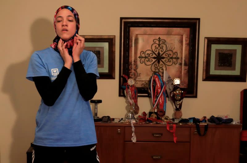 Egyptian Taekwondo practitioner Wahba dons a sports hijab next to her trophies and medals at her homein Cairo