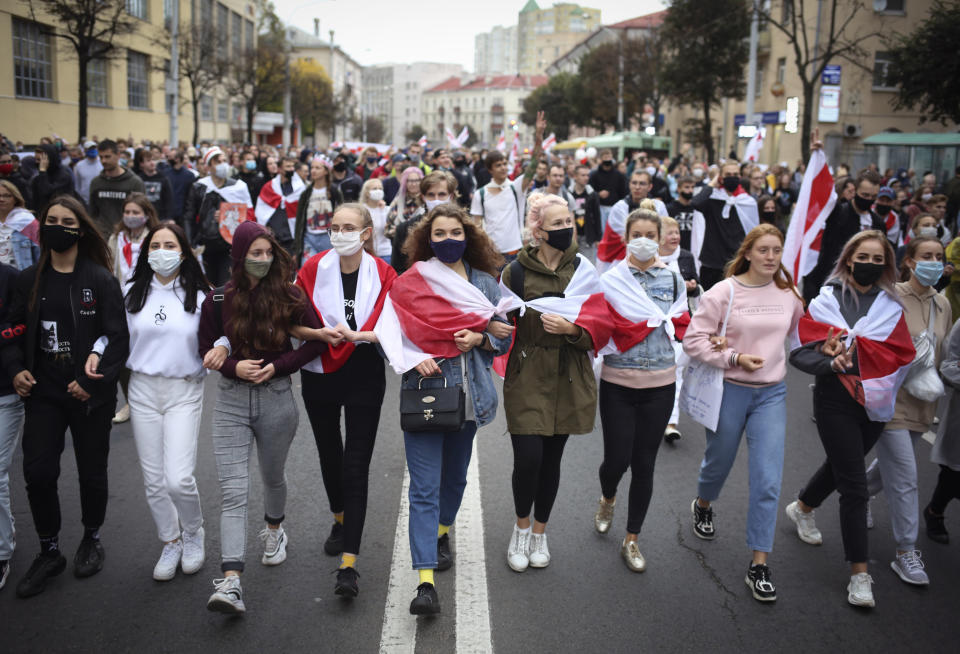 Young people some wearing old Belarusian national flags draped around them, march during an opposition rally to protest the official presidential election results in Minsk, Belarus, Sunday, Sept. 27, 2020. Hundreds of thousands of Belarusians have been protesting daily since the Aug. 9 presidential election. (AP Photo/TUT.by)