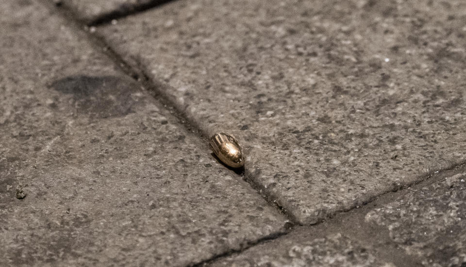 A bullet lies on the sidewalk near a restaurant at the scene of a shooting in central Hanau, Germany Thursday, Feb. 20, 2020. Eight people were killed in shootings in the German city of Hanau on Wednesday evening, authorities said. (Andreas Arnold/dpa via AP)