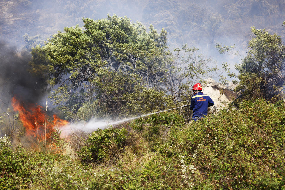 A member of anti-forest fire team puts out flames burning in Capaci, near Palermo, in Sicily, southern Italy, Wednesday, July 26, 2023. On the island of Sicily, two people were found dead Tuesday in a home burned by a wildfire that temporarily shut down Palermo's international airport, according to Italian news reports. Regional officials said 55 fires were active on Sicily, amid temperatures in the 40s Celsius. (Alberto Lo Bianco/LaPresse via AP)