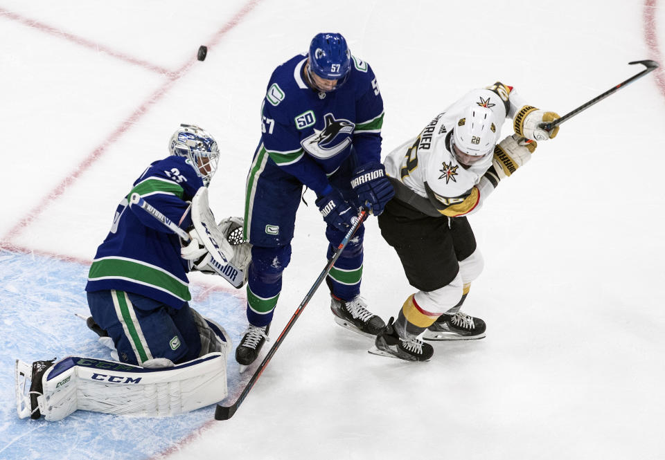 Vegas Golden Knights' William Carrier (28) and Vancouver Canucks' Tyler Myers (57) battle in front as goalie Jacob Markstrom (25) makes the save during the second period of an NHL Western Conference Stanley Cup playoff game, Sunday, Aug. 30, 2020, in Edmonton, Alberta. (Jason Franson/The Canadian Press via AP)