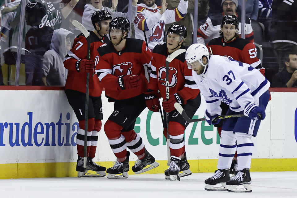 New Jersey Devils defenseman Dougie Hamilton (7) and teammates celebrate his goal, as Toronto Maple Leafs defenseman Timothy Liljegren (37) skates past during the third period of an NHL hockey game Wednesday, Nov. 23, 2022, in Newark, N.J. The Maple Leafs won 2-1. (AP Photo/Adam Hunger)