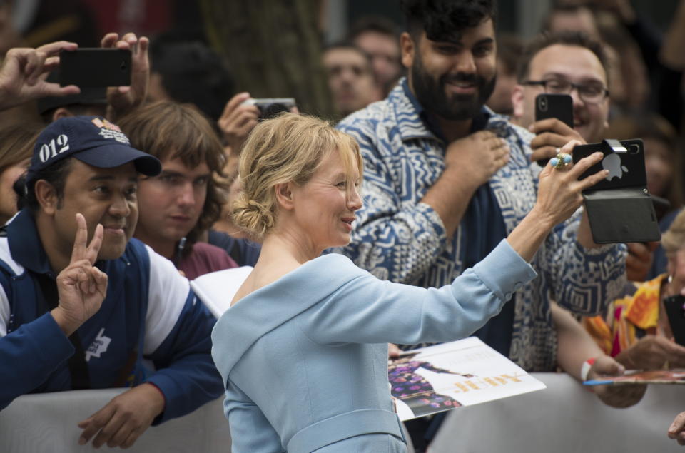 FILE - Actress Renee Zellweger take a photograph with her fans at the red carpet premiere for the film "Judy" during the 2019 Toronto International Film Festival in Toronto on Sept. 10, 2019. This year, three of the four major fall film festivals, including TIFF are going forward despite the pandemic. Those at the Venice Films Festival acknowledge it hasn’t been anywhere near the same. Masked moviegoers in set-apart seats. A barrier walls off the red carpet to discourage crowds of onlookers. Greetings are kiss-less. TIFF opens on Thursday. (Tijana Martin/The Canadian Press via AP, File)