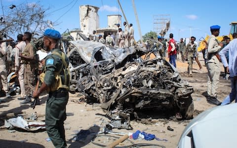 Security officers gather at the scene of a large explosion near a check point in Mogadishu - Credit: REX