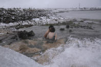 An Israeli couple kiss as they bathe in a hot water coming out of a pipe from a drilling project which exposed a subterranean hydrothermal spring, at a snow-covered reservoir next to Mount Bental in the Israeli-controlled Golan Heights, near the Israeli border with Syria Wednesday, Jan. 19, 2022. Snow fell in parts of the Middle East as a winter storm swept through the region. (AP Photo/Ariel Schalit)