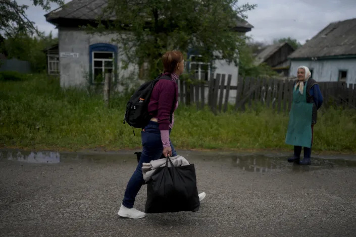 Nila Zelinska, left, walks to her home town after escaping war in Potashnya, on the outskirts of Kyiv, Ukraine, Tuesday, May 31, 2022. Zelinska's home was destroyed during attacks. (AP Photo/Natacha Pisarenko)