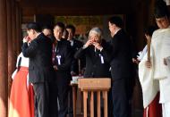 Japanese lawmakers, led by former Health Minister Hidehisa Otsuji (C), drink sake to 'purify' as they visit to the Yasukuni shrine to honour the war dead, in Tokyo, on April 22, 2015