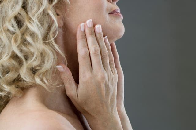 B7MGYG A middle-aged woman looking at her face in the mirror Woman, middle, age, beauty, hands, face, skin,