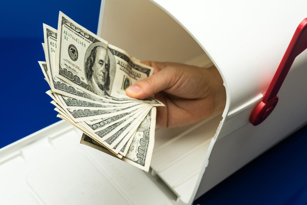 hand holding $100 bills in mailbox