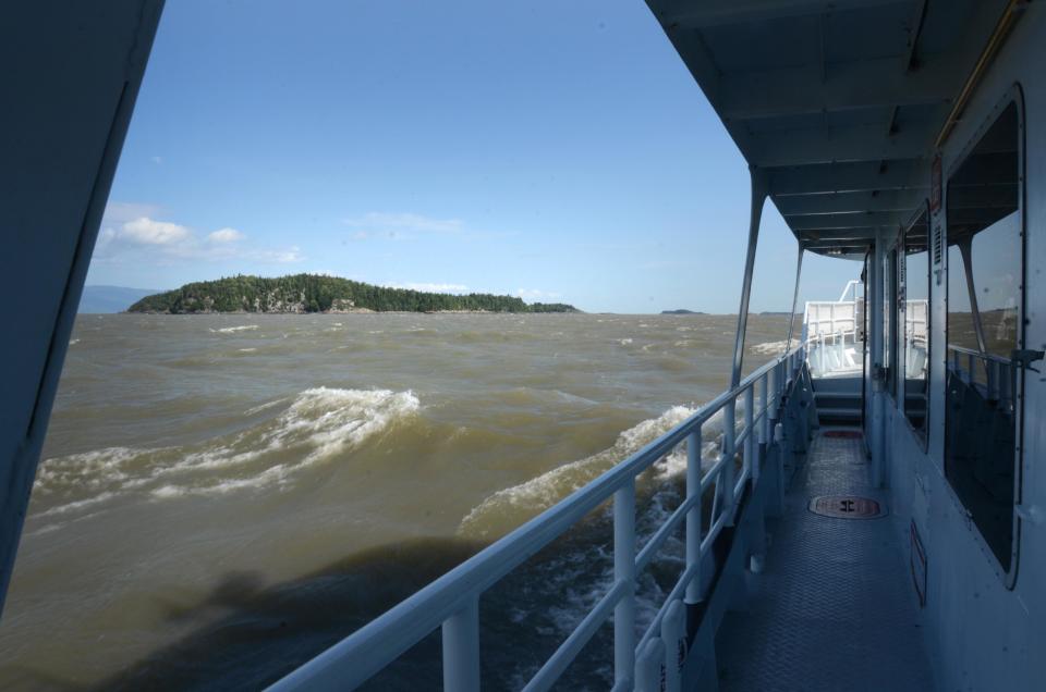 In this photo taken Aug. 15, 2013, a boat carrying scores of passengers steams towards Ile-aux-Grues in the St. Lawrence River. The Quebec island offers quiet roads and stunning river vistas for cyclists and lovers of solitude. (AP Photo/Calvin Woodward)