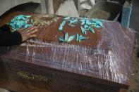 A relative of Joaquin Alonso touches the coffin of the 58-year-old who died of COVID-19 during his burial at the cemetery "Martires 19 de Julio" in Comas on the outskirts of Lima, Peru, Tuesday, July 28, 2020. Peruvian authorities and the Pan American Health Organization are investigating whether the country failed to classify just over 27,000 deaths as caused by the novel coronavirus, a figure that could more than double the country's official death toll from the disease. (AP Photo/Rodrigo Abd)