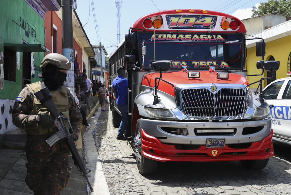 Un soldado del ejército camina frente a un autobús en Comasagua, El Salvador, el lunes 3 de octubre de 2022. Más de 2.000 soldados y policías rodearon y cerraron Comasagua el domingo para buscar a pandilleros acusados de asesinato. (Foto AP/Salvador Meléndez)