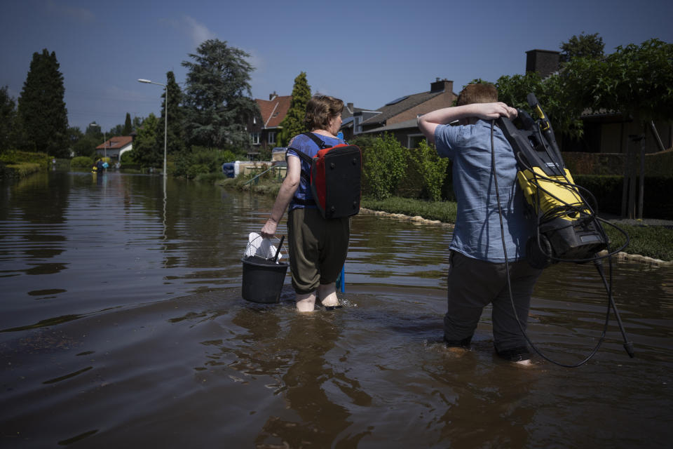 Residents return to their homes with cleaning materials in the town of Brommelen, Netherlands, Saturday, July 17, 2021. In the southern Dutch province of Limburg, which also has been hit hard by flooding, troops piled sandbags to strengthen a 1.1-kilometer (0.7 mile) stretch of dike along the Maas River, and police helped evacuate low-lying neighborhoods. (AP Photo/Bram Janssen)