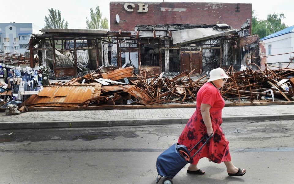 A woman walks past a ruined building in central Donetsk