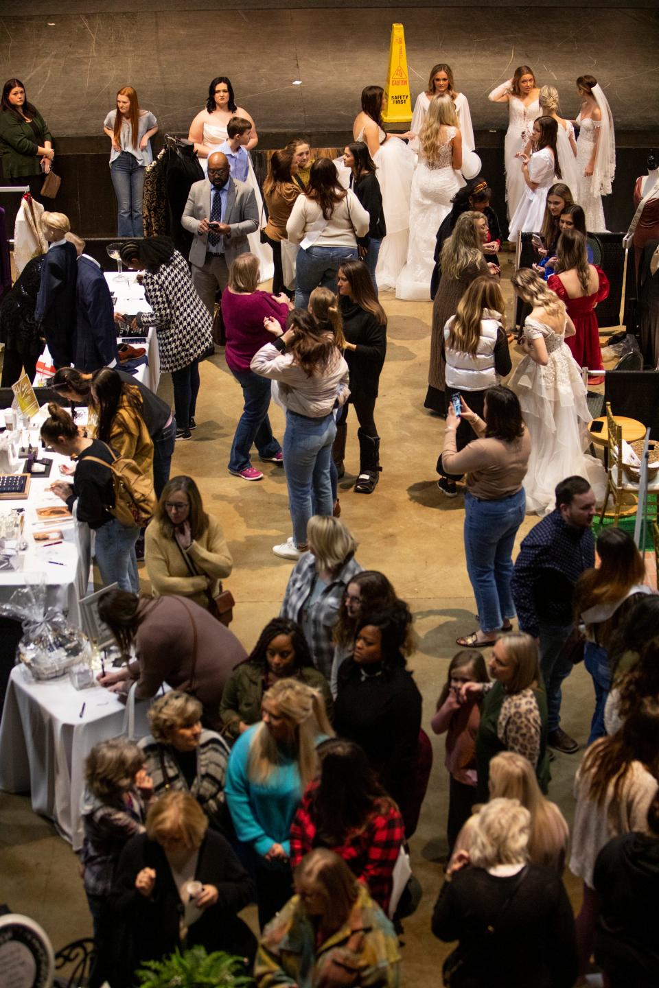 Attendees take photos and look at vendors’ booths as models show off different wedding dresses from My Best Friend Jenna during the Jackson Bridal Show at the Carl Perkins Civic Center on Sunday, January 8, 2023, in Jackson, Tenn. 