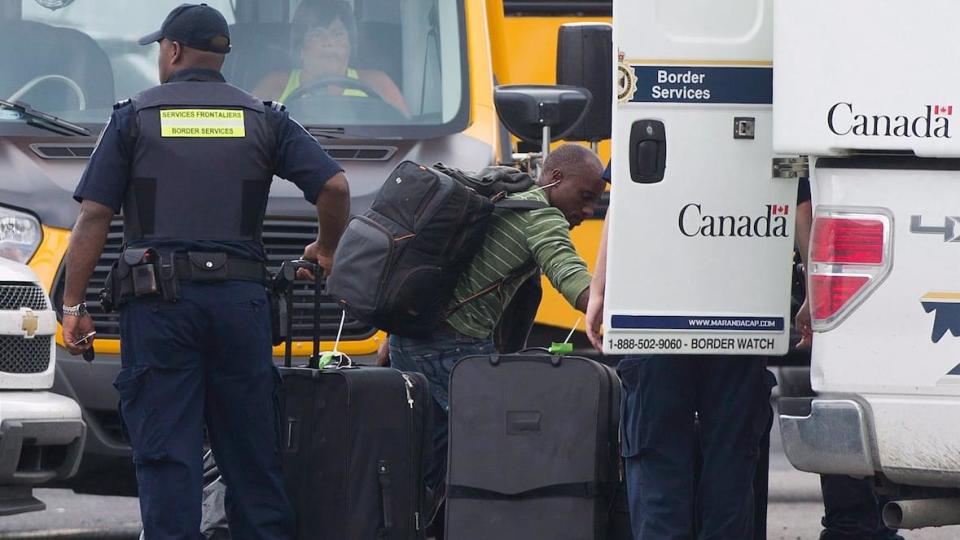 A man removes his belongings from a CBSA truck at a processing center for asylum seekers in Quebec (File photo).