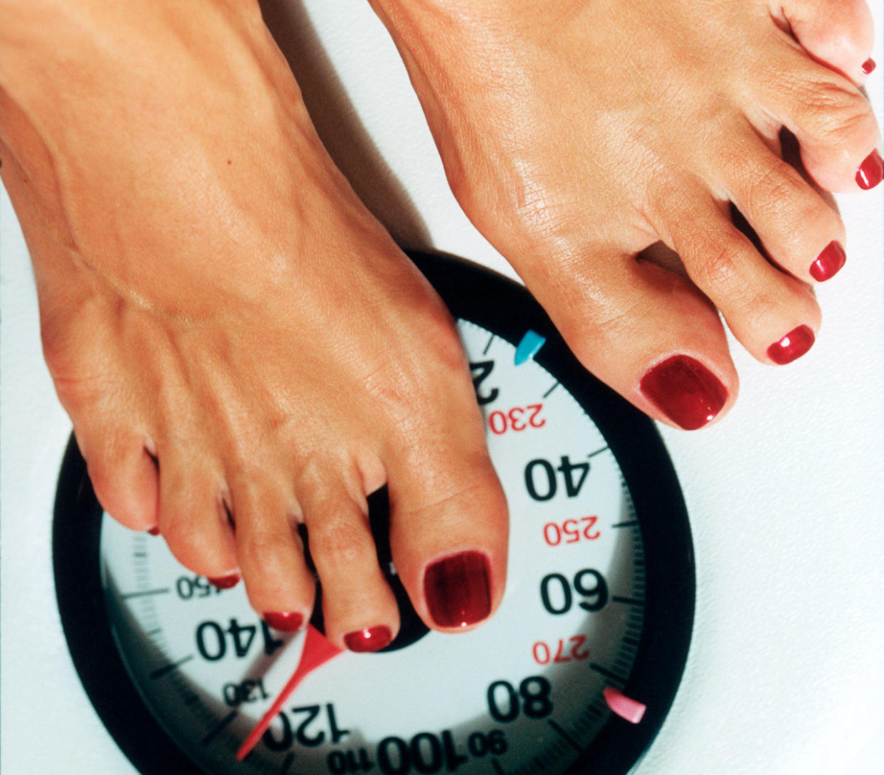 close up of a women's feet standing on a weight scale. 