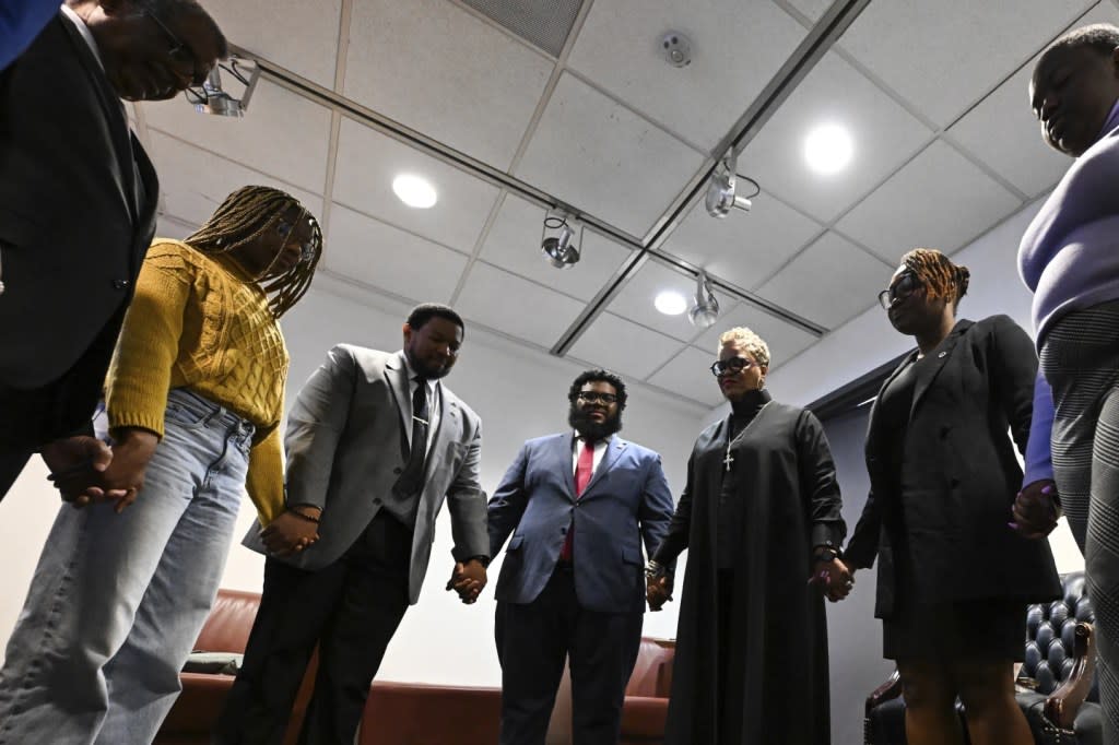 Rev. Gina Stewart, third from right, holds hands with students and faculty of Howard University before church service at Rankin Chapel, Sunday, April 7, 2024, in Washington. (AP Photo/Terrance Williams)