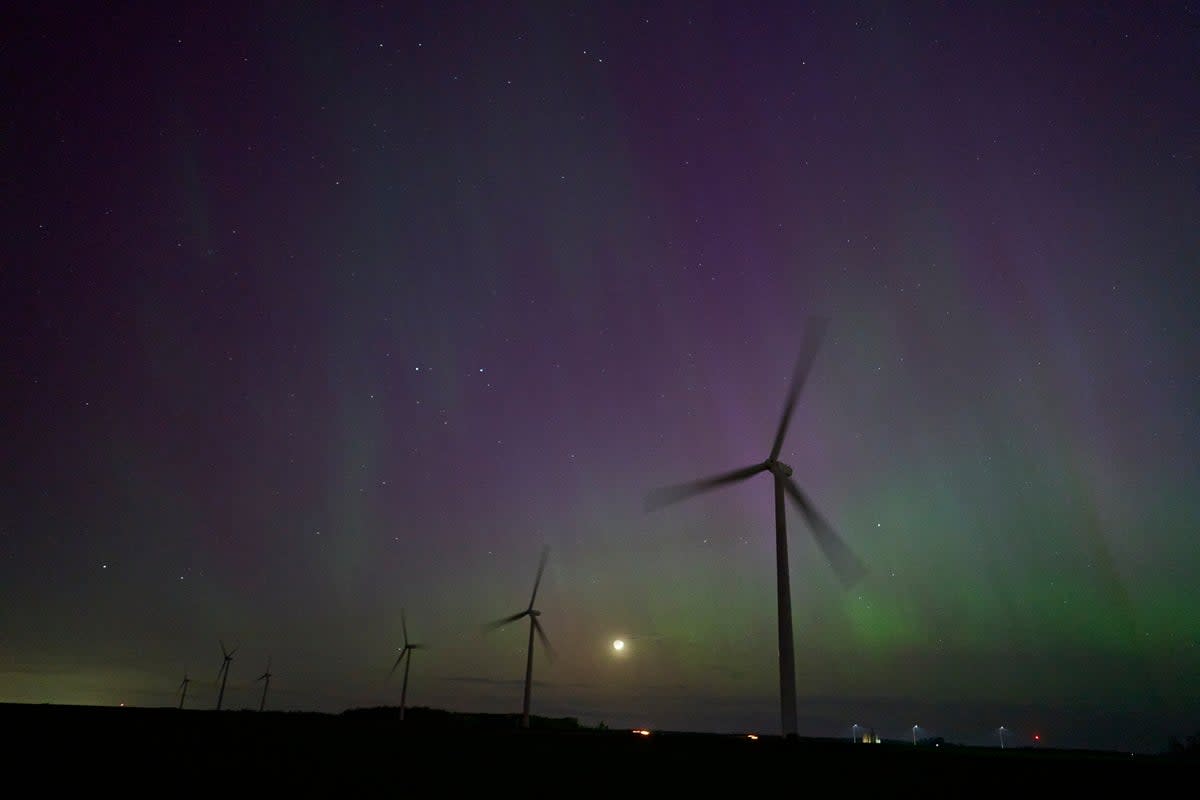 Windmills turn in a field near London, Ontario as the Northern lights or aurora borealis illuminate the night sky during a geomagnetic storm on May 10, 2024 (AFP via Getty Images)