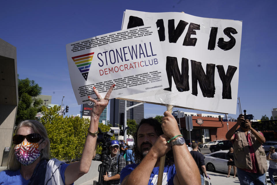 Jane Wishon, Political Vice President of the Stonewall Democratic Club, left, holds a sign in front of an unidentified demonstrator supporting Dave Chappelle, outside the Netflix building in the Hollywood section of Los Angeles, Wednesday, Oct. 20, 2021. Critics and supporters of Chappelle's Netflix special and its anti-transgender comments gathered outside the company's offices Wednesday. (AP Photo/Damian Dovarganes)