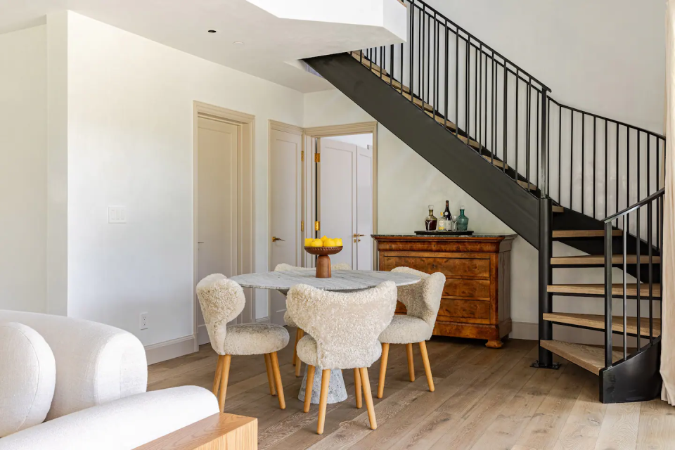 A small dining set with Sherpa chairs and a spiral staircase in the background