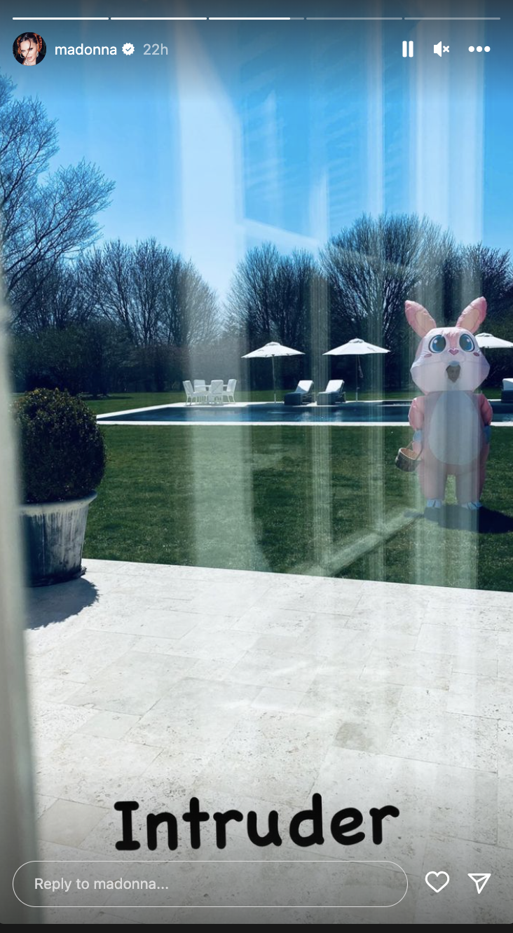 A person in a pink bunny costume. stands outside a home  (@Maddona / Instagram)