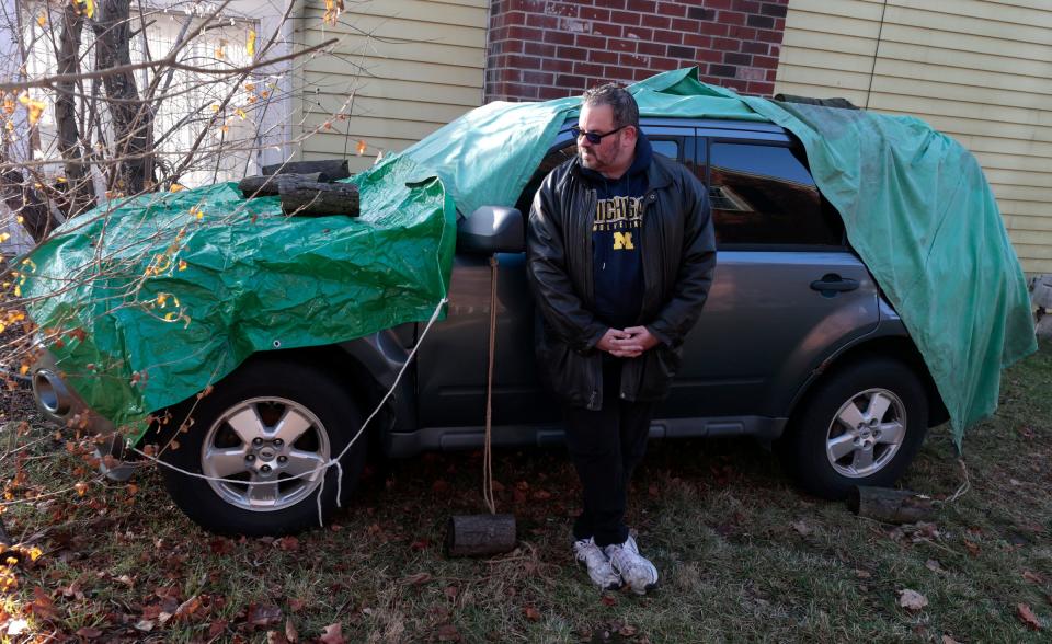 Hunt Gersin, 55 of West Bloomfield with his damaged 2010 Ford Escape on the side of his home on Thursday, December 7, 2023. Last April, Gersin was driving when his left front tire came off damaging his SUV, not allowing his front driver's side door to open. Midas had rotated his tires and their insurance company offered him $1,900 but estimates to repair his vehicle are around $4,500. He uses it as a food delivery driver and wants Midas to pay for the full repair plus compensation for his lost income.