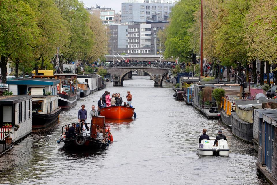 A range of houseboats moored on both sides of an Amsterdam river by the Noordermarkt.