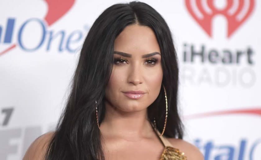 Demi Lovato posing in gold hoop earrings