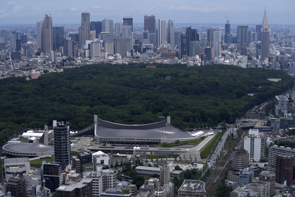 Yoyogi National Stadium, where handball will be held for Tokyo 2020 Olympics, is seen Saturday, July 10, 2021, in Tokyo as Meiji Jingu Shrine and Shinjuku skyline are viewed in the back ground. The Yoyogi National Stadium was the architectural jewel of the 1964 Tokyo Olympics. (AP Photo/Kiichiro Sato)